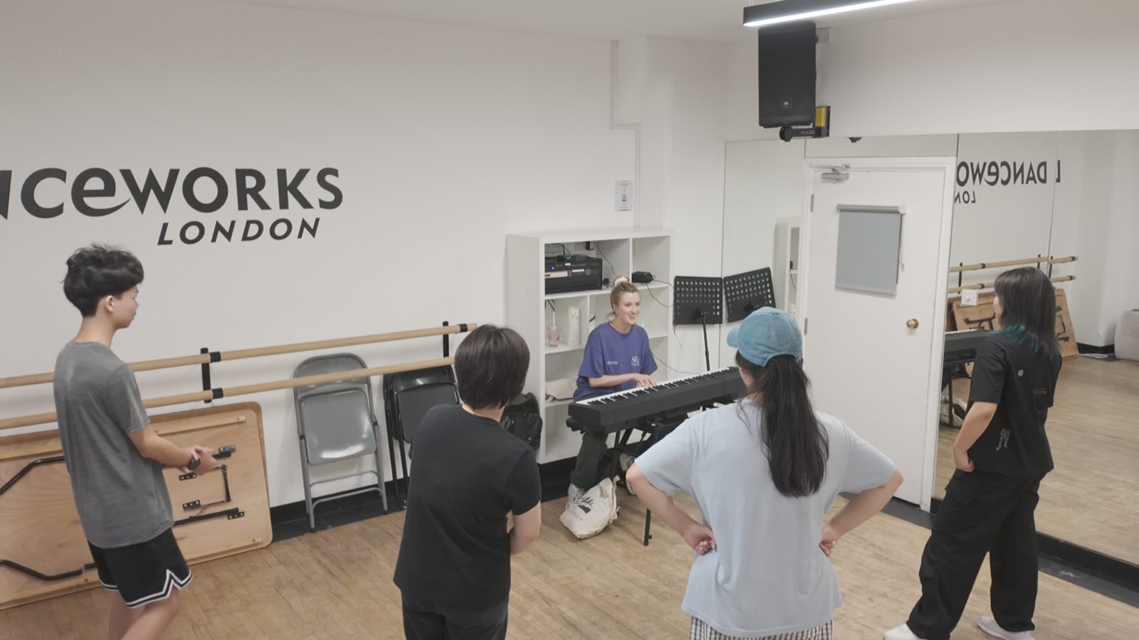 A group class with a vocal coach at the piano in a London studio